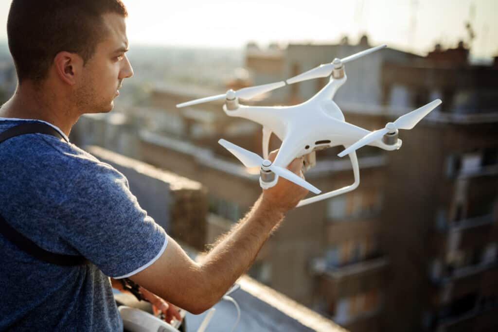 Junger Techniker fliegt UAV-Drohne mit Fernbedienung im Freien